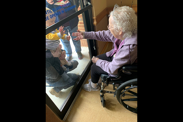 Gladys visiting with her great-grandson at the window