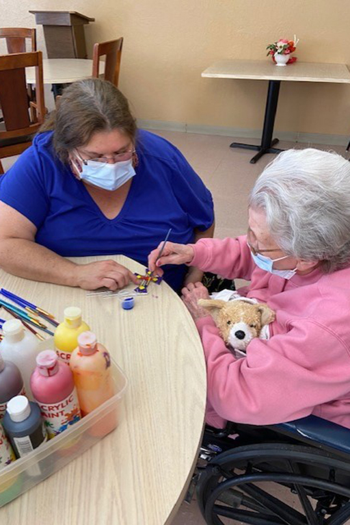 Bruceton-Hollow Rock Activity Director Hyacie Corbitt helping resident Betty Brown paint a suncatcher for Tourist Day