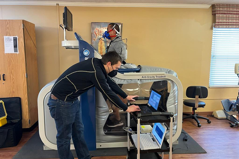 Mike Belbis runs on the AlterG while Michael Holmes watches the data.